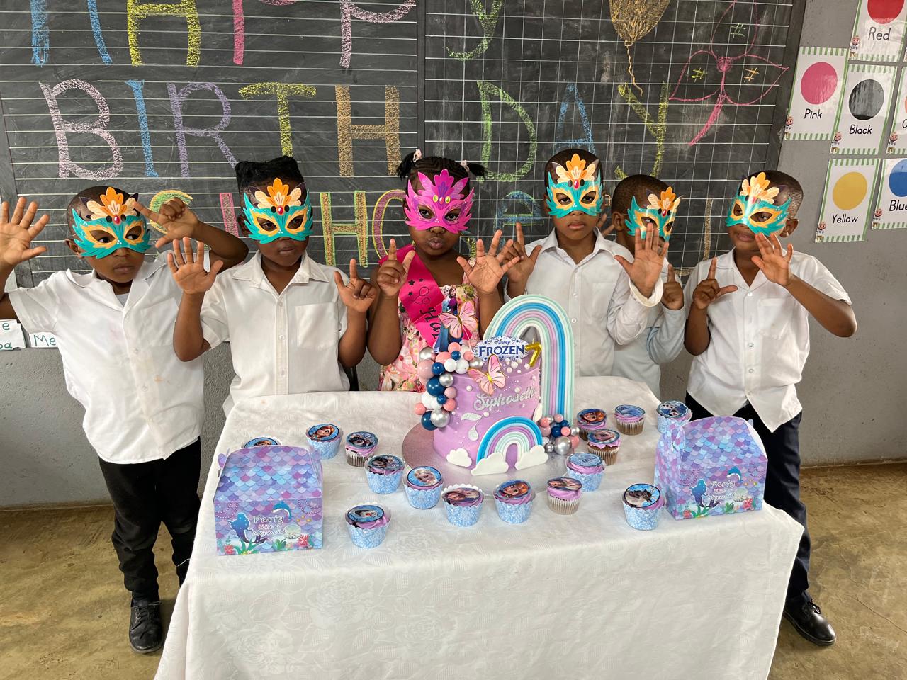 Learners celebrating a birthday with masks and cake