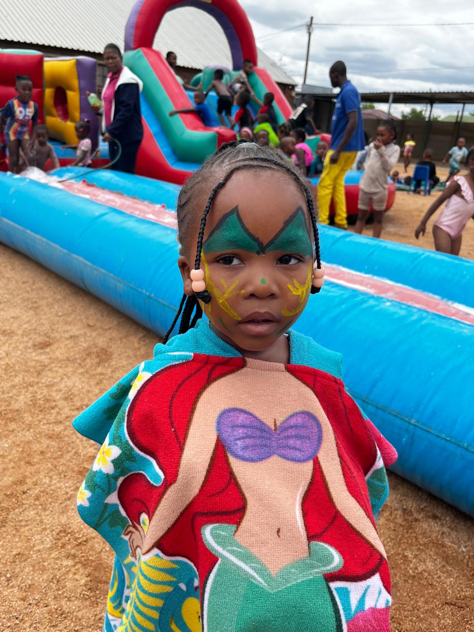 Learner enjoying water day with face paint and inflatable slide